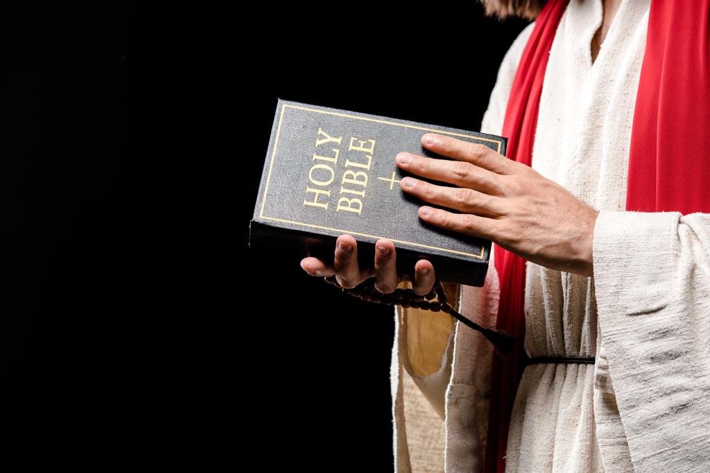 обрезанный вид проведения священной библии изолированы на черном
 - Фото, изображение