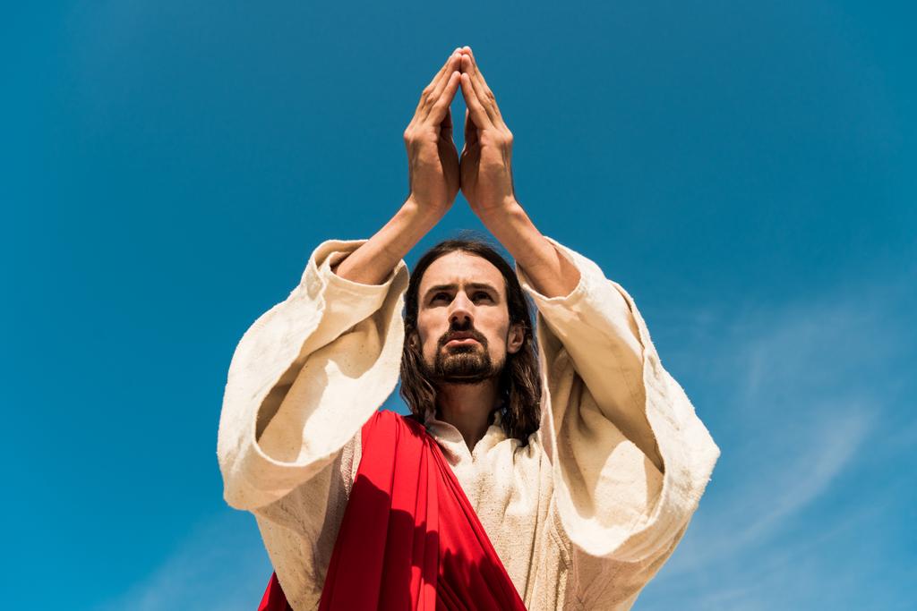 vue à angle bas de Jésus avec les mains priantes contre le ciel bleu
  - Photo, image