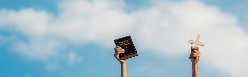 panoramische foto van de man met de Heilige Bijbel en kruis tegen blauwe hemel met wolken - Foto, afbeelding