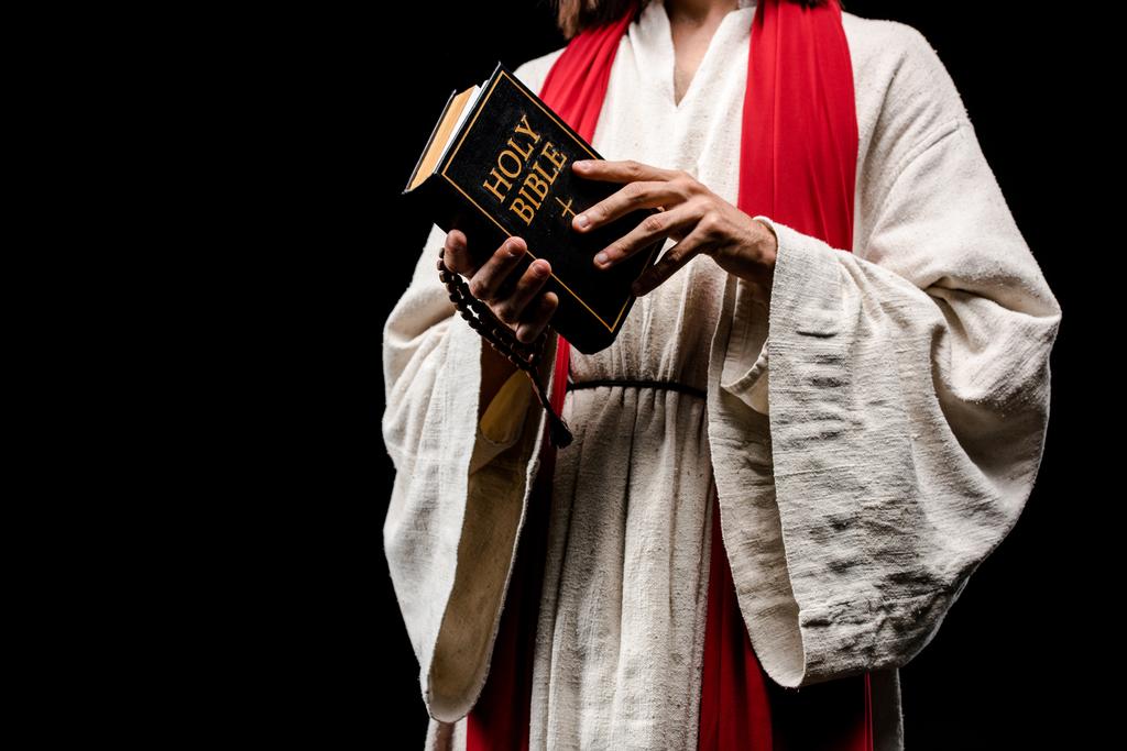 vista ritagliata dell'uomo che tiene il libro con la sacra Bibbia isolata su nero
  - Foto, immagini