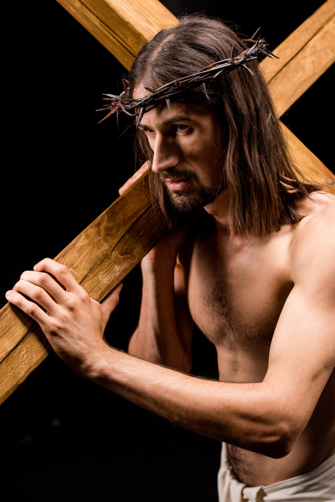 黒で隔離された木製の十字架を保持するスパイクを持つ花輪のイエス  - 写真・画像