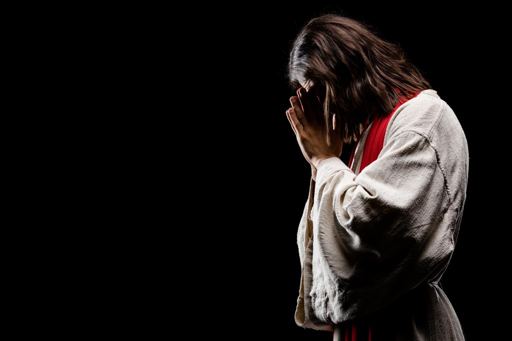 Религиозный человек покрывает лицо, молясь изолированно на черном
  - Фото, изображение
