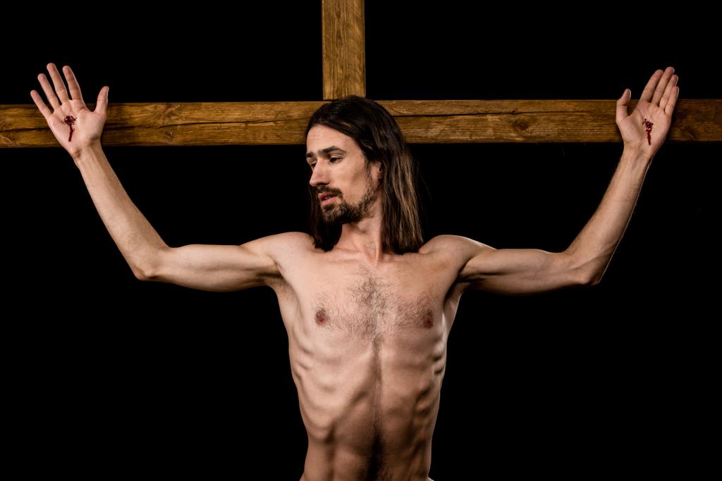 homem sem camisa crucificado na cruz de madeira isolado em preto
  - Foto, Imagem