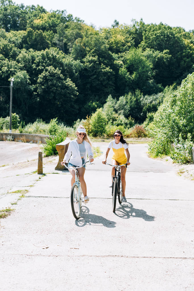 meninas loiras e morenas felizes andando de bicicleta no verão
 - Foto, Imagem