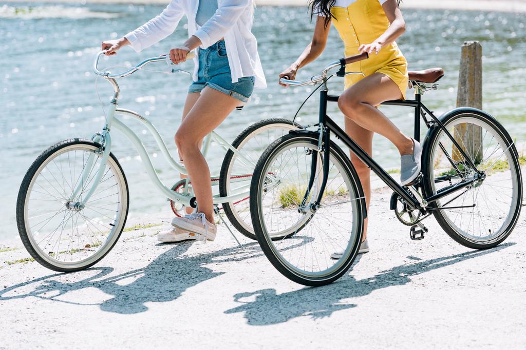 vista cortada de meninas andando de bicicleta perto do rio no verão
 - Foto, Imagem