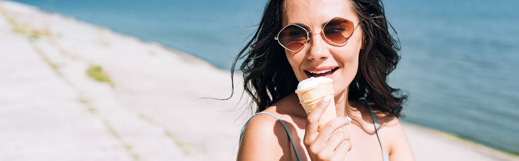colpo panoramico di ragazza bruna mangiare gelato vicino al fiume in estate
 - Foto, immagini