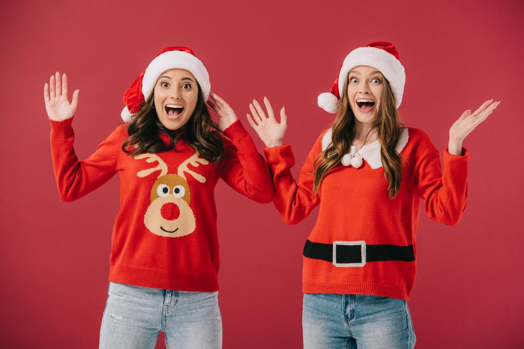 houkutteleva ja hymyilevä naisten villapaidat ja santa hatut ojennetut kädet eristetty punaisella
  - Valokuva, kuva