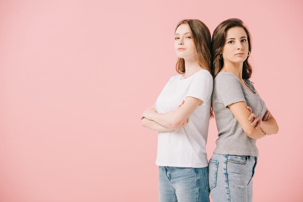 atrakcyjne kobiety w koszulkach pokazujące skrzyżowane ramiona patrząc na kamerę na różowo - Zdjęcie, obraz