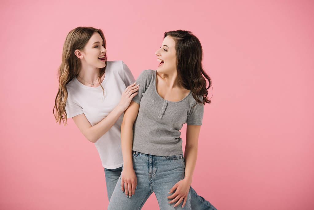 mulheres atraentes e sorridentes em camisetas olhando umas para as outras isoladas em rosa
 - Foto, Imagem