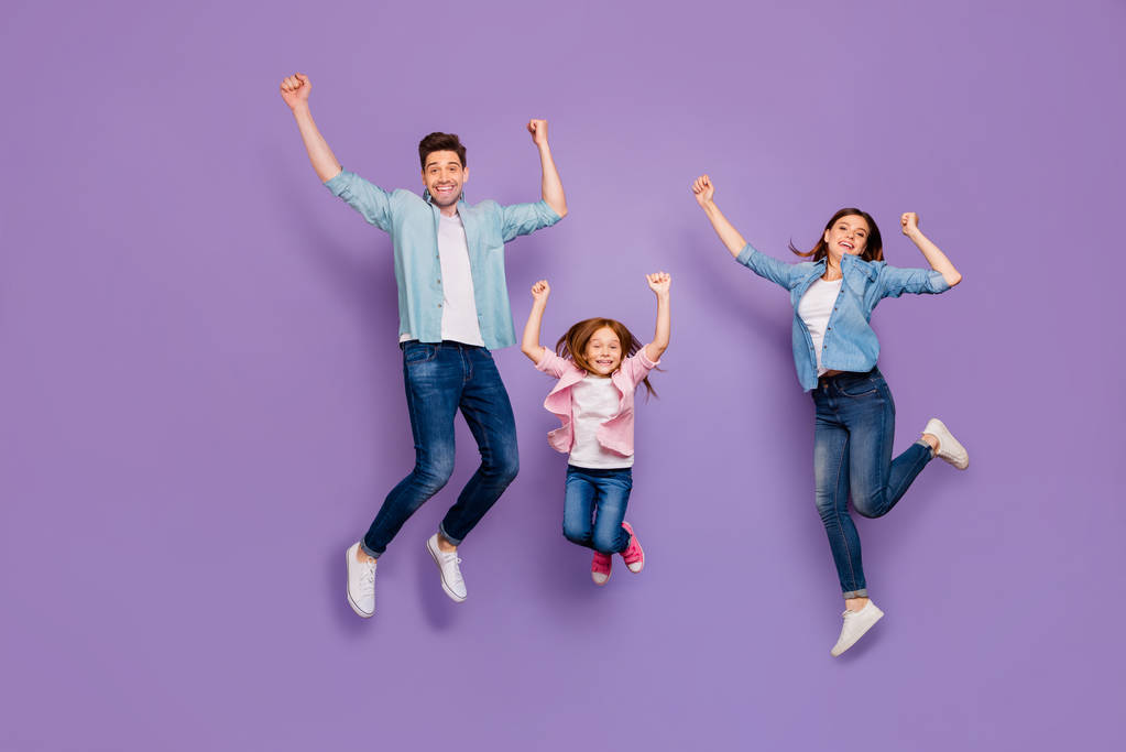 Volledige lengte foto van drie vrolijke Jumping hoge familieleden dragen casual kleding geïsoleerd paarse achtergrond - Foto, afbeelding