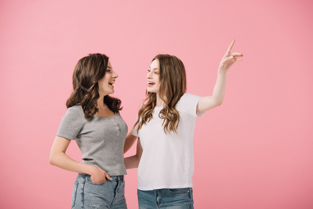 donne attraenti e sorridenti in t-shirt che puntano con il dito isolato sul rosa
 - Foto, immagini