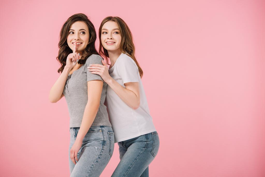 aantrekkelijke vrouwen in t-shirts tonen shh gebaar geïsoleerd op roze - Foto, afbeelding