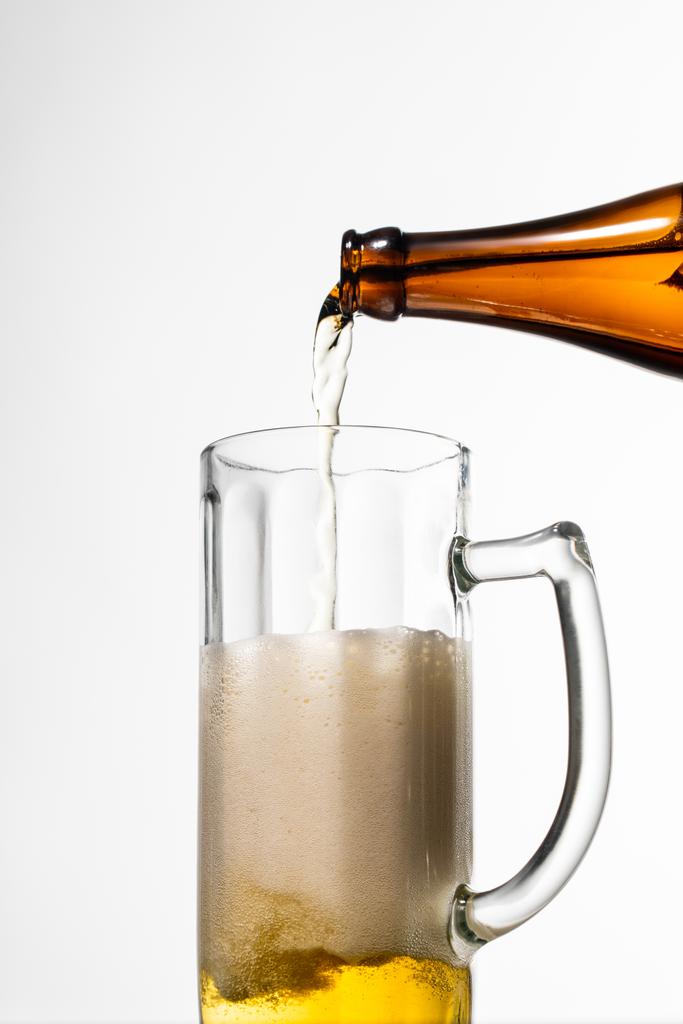 ボトルからガラスに注ぐビールは、白に分離された泡で - 写真・画像