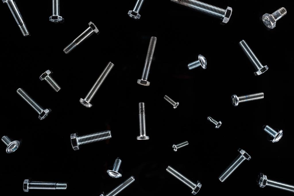 top view of scattered metal bolts pattern isolated on black - Photo, Image