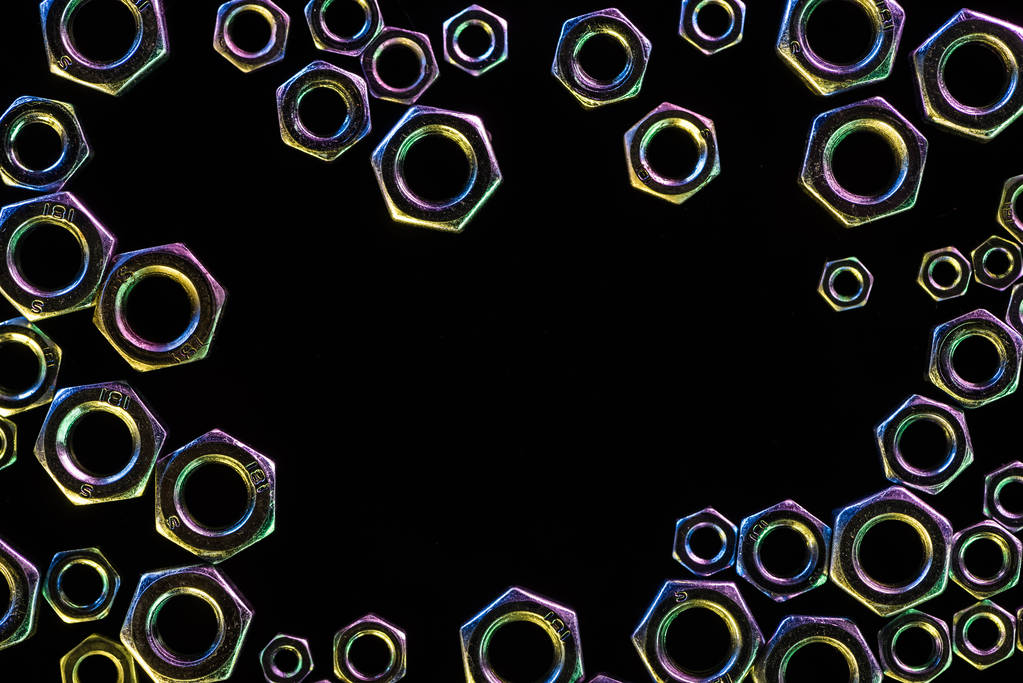 vista de cerca de diversas tuercas metálicas dispersas aisladas en negro con espacio de copia
 - Foto, Imagen