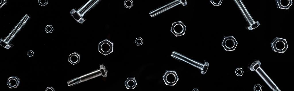 panoramic shot of scattered metal bolts and nuts pattern isolated on black - Photo, Image