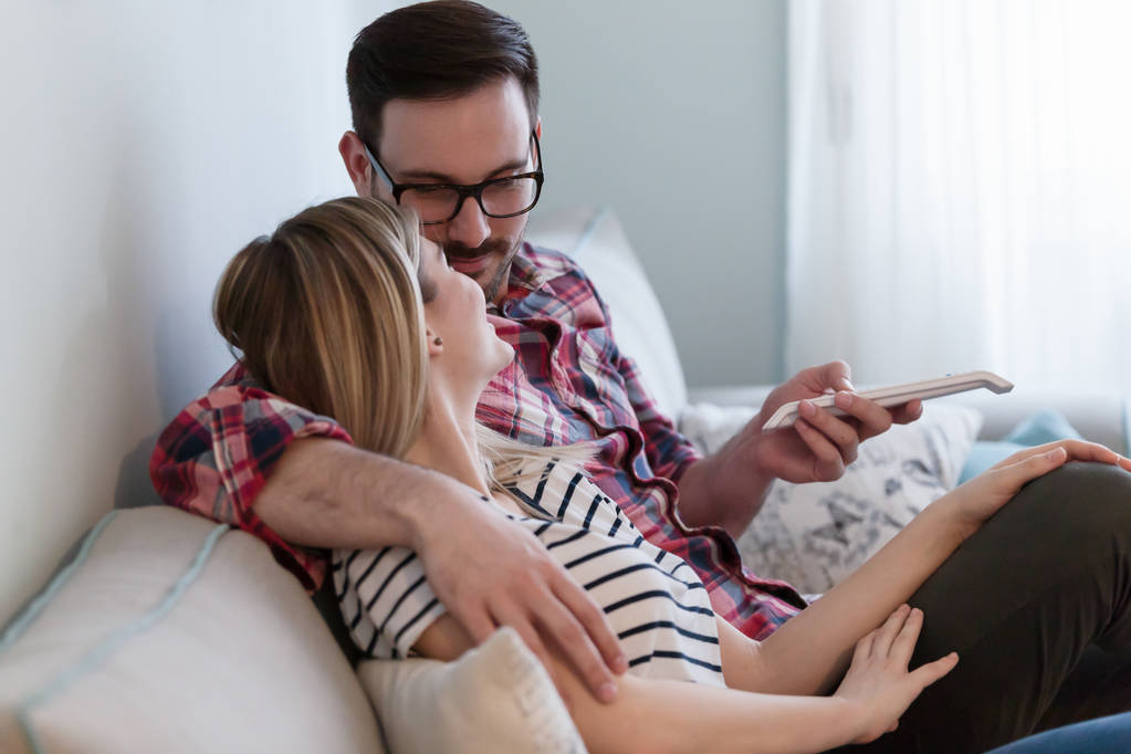 Giovane coppia felice guardando la tv insieme in soggiorno
 - Foto, immagini