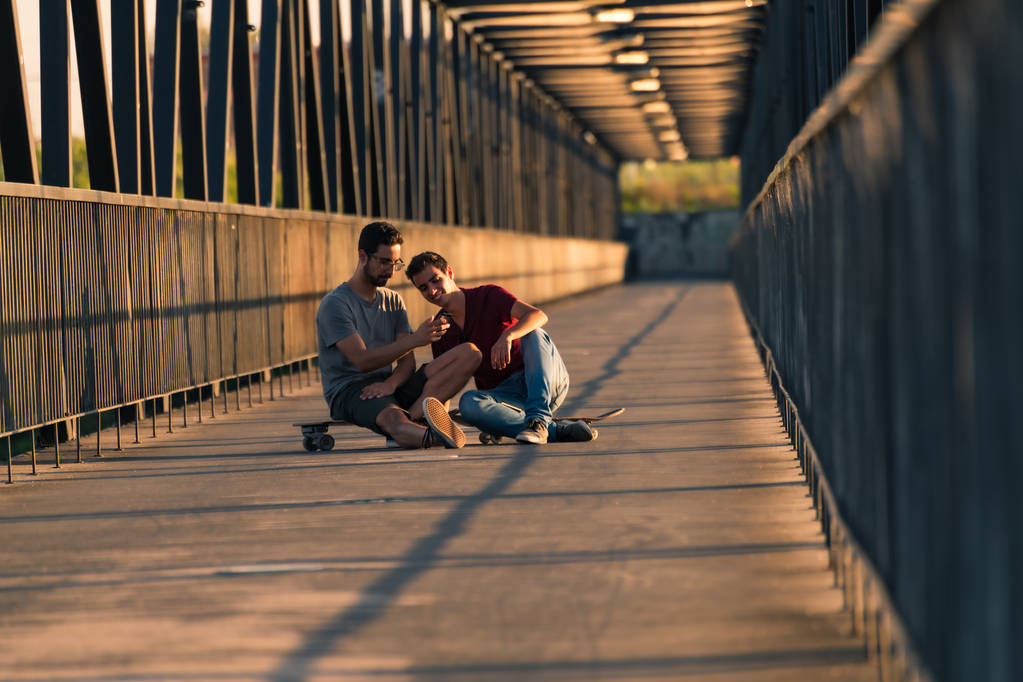 Mladí skateboardisté sedí na svých deskách - Fotografie, Obrázek