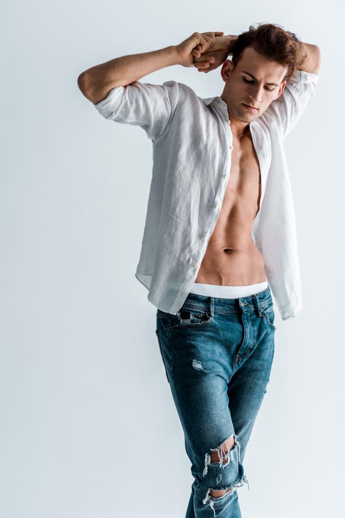 sexy hombre en azul jeans y camisa de pie aislado en blanco
  - Foto, Imagen