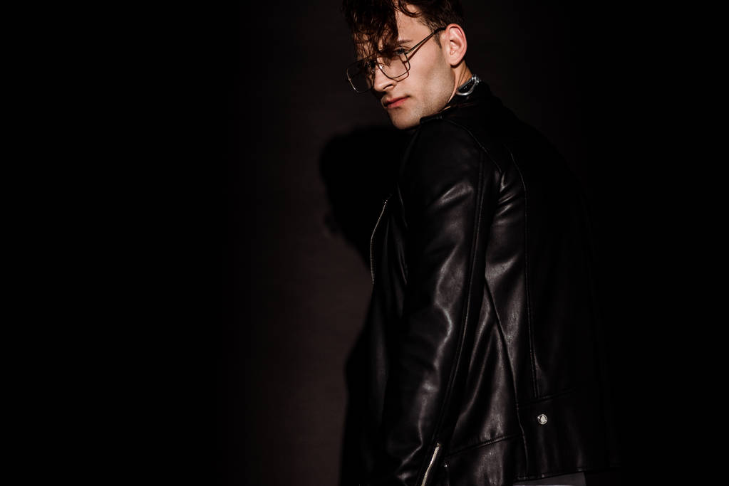 hombre de moda en gafas y chaqueta de cuero de pie en negro
  - Foto, Imagen