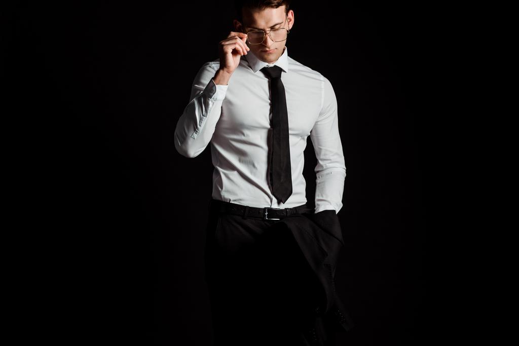 guapo hombre de negocios tocando gafas aisladas en negro
  - Foto, Imagen