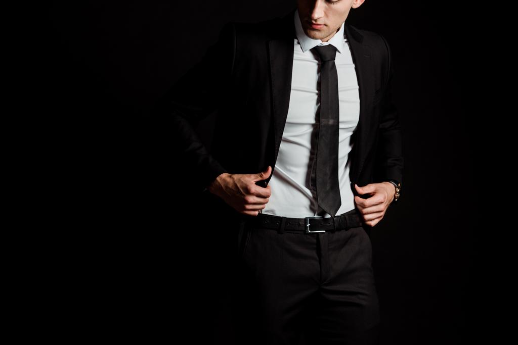 περικομμένη όψη του άντρα άγγιγμα κοστούμι απομονώνεται σε μαύρο  - Φωτογραφία, εικόνα