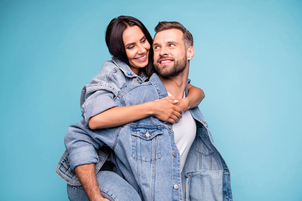 Πορτρέτο του γοητευτικό ζευγάρι αγκαλιάζει κοιτάζοντας φορώντας ντένιμ τζιν απομονώνεται πάνω από μπλε φόντο - Φωτογραφία, εικόνα