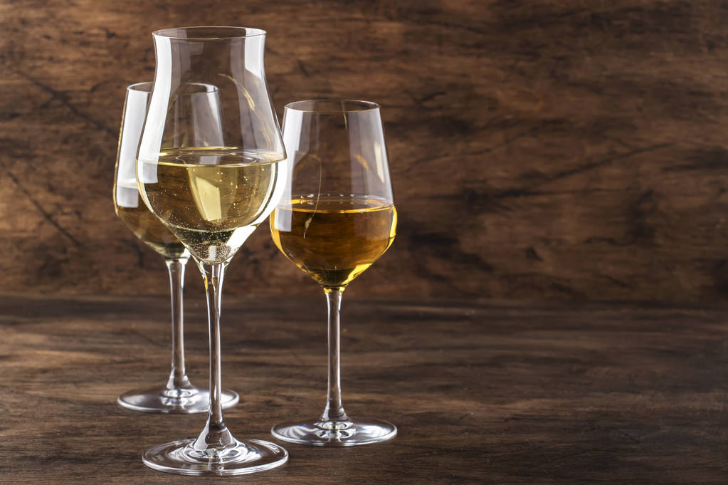 Zestaw białego wina. Degustacja wina, najpopularniejsze odmiany białych win w kieliszkach do wina na drewnianym stole w stylu rustykalnym, selektywne skupienie - Zdjęcie, obraz