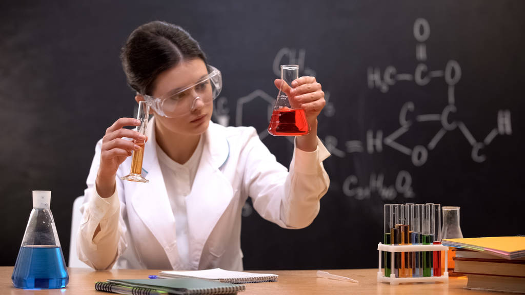 Chemikerin untersucht Anwesenheit von Sedimenten in Kolben mit roter Flüssigkeit im Labor - Foto, Bild