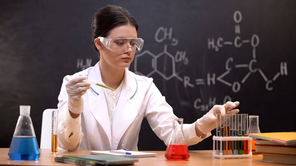 Femme scientifique tenant une pipette avec un liquide et prenant un tube à essai avec un réactif
 - Photo, image