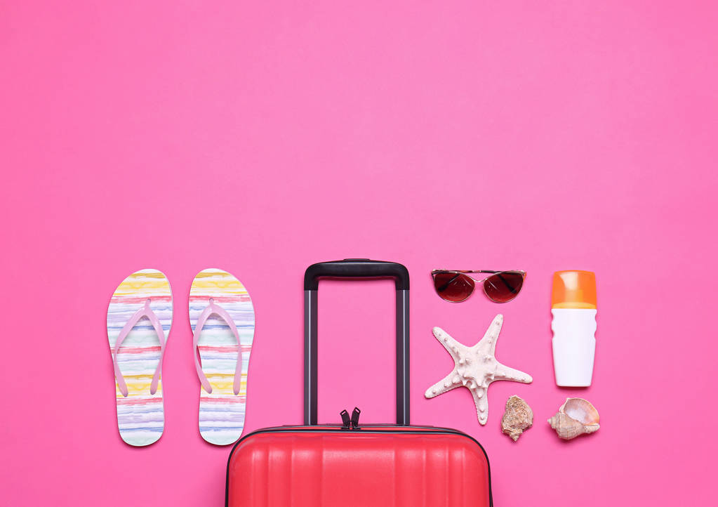 Maleta roja y objetos de playa sobre fondo rosa, plano. Espacio para texto
 - Foto, Imagen