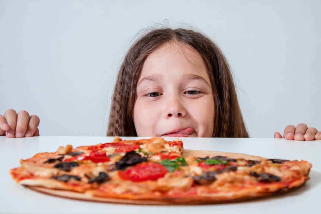 La petite fille regarde la pizza. Enfant trouvé pizza
 - Photo, image