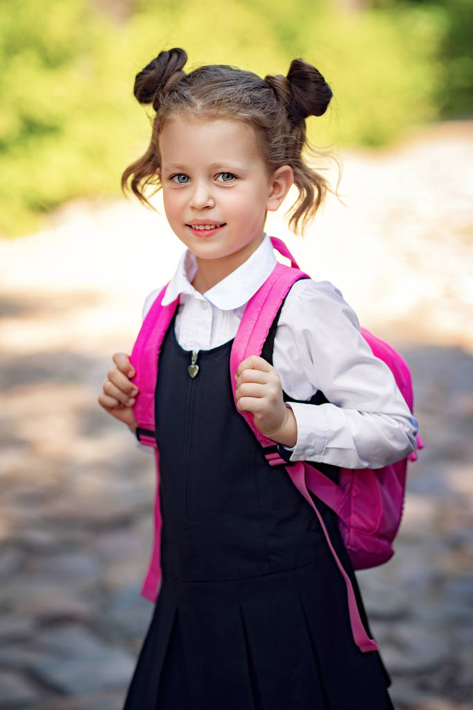 Uśmiechnięta uczennica ubrana w szkolny plecak. Portret szczęśliwej kaukaski młoda dziewczyna poza szkołą podstawową. Uśmiechnięta uczennica patrząc na kamerę. - Zdjęcie, obraz