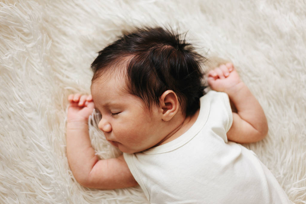 Κοιμάται μωρό με όμορφα μαλλιά στο πίσω μέρος σε λευκό κρεβάτι - Φωτογραφία, εικόνα