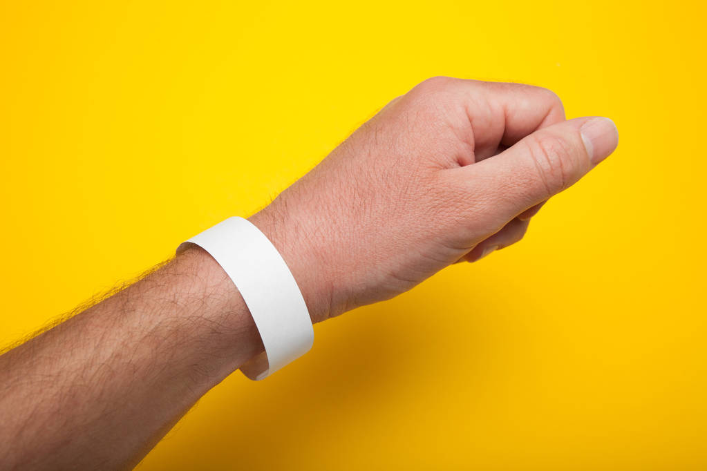 weißes Armband, Armband-Attrappe für Veranstaltung auf gelbem Hintergrund. - Foto, Bild
