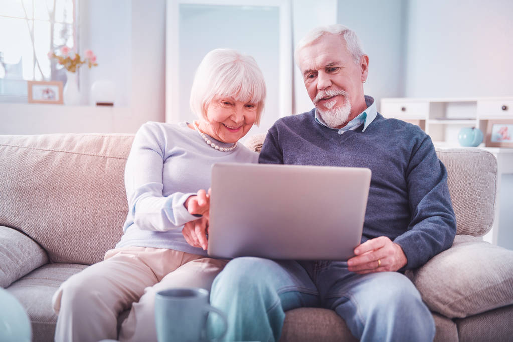 Moderna pareja jubilada sintiéndose involucrada en ver películas en su computadora portátil
 - Foto, imagen