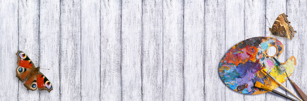 Палитра для масляных красок с кисточками и бабочкой на деревянном фоне
 - Фото, изображение