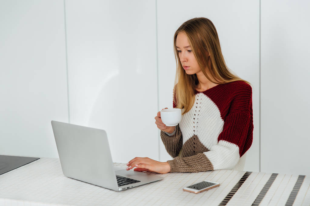 Dizüstü bilgisayar kullanarak ve evde çay içme odaklı güzel kız - Fotoğraf, Görsel