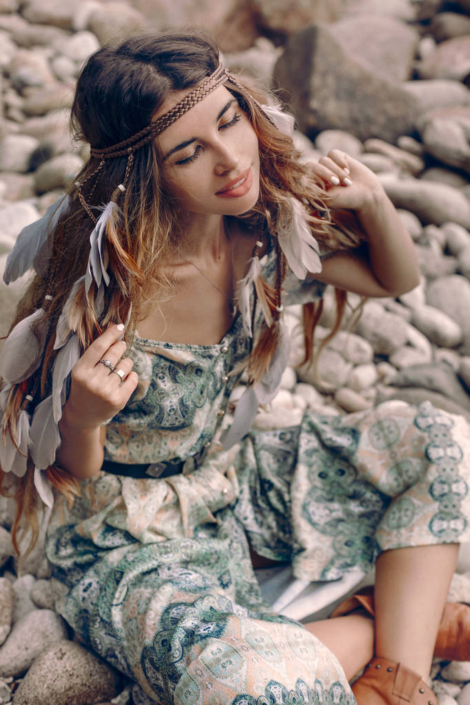 atrakcyjna młoda modna kobieta siedzi na kamiennej plaży - Zdjęcie, obraz