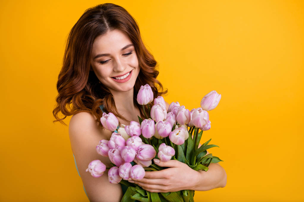 Foto von hübschen Dame hält großen Haufen rosa Tulpen in den Händen tragen Tank-Top isoliert gelben Hintergrund - Foto, Bild