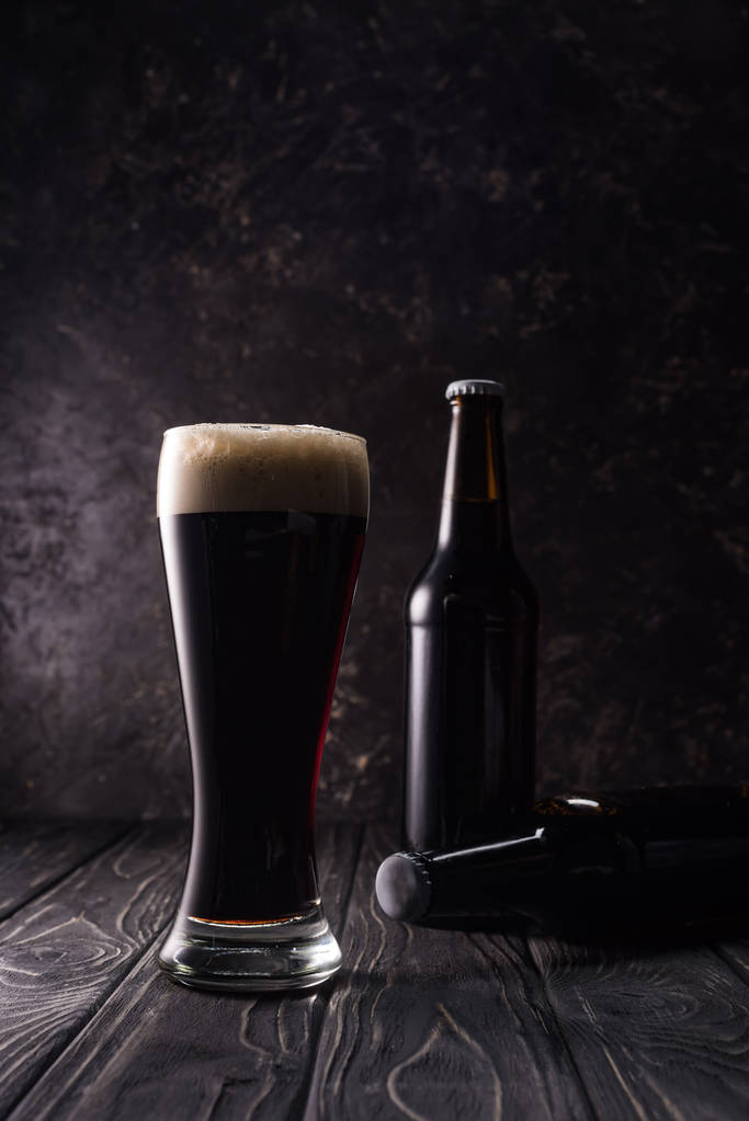 láhve a sklenice piva ve stínu na dřevěném stole - Fotografie, Obrázek