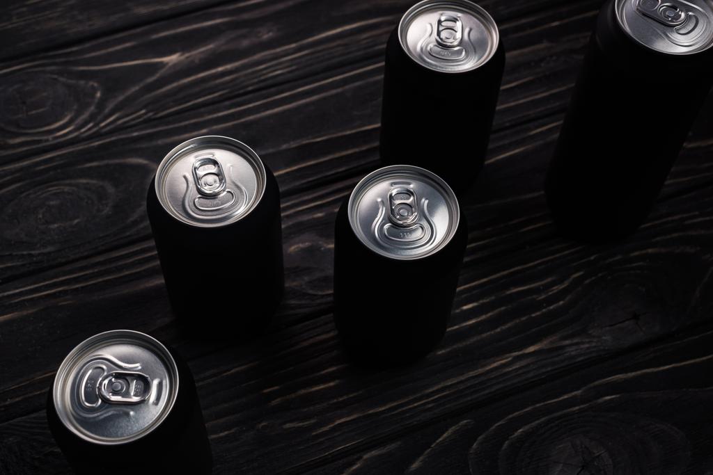 чорні металеві банки пива на дерев'яному столі
  - Фото, зображення