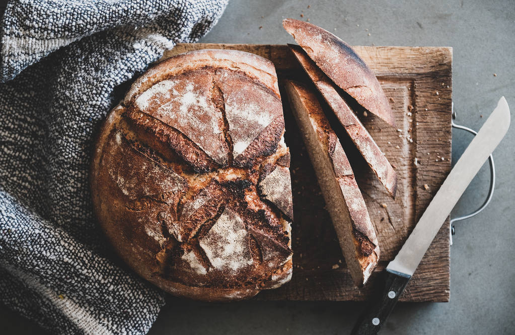 Płasko-lay świeżo upieczony chleb chlebowy chleba i chleba plasterki na rustykalny drewniany deska nad szarym betonowe tło stołu, widok z góry - Zdjęcie, obraz