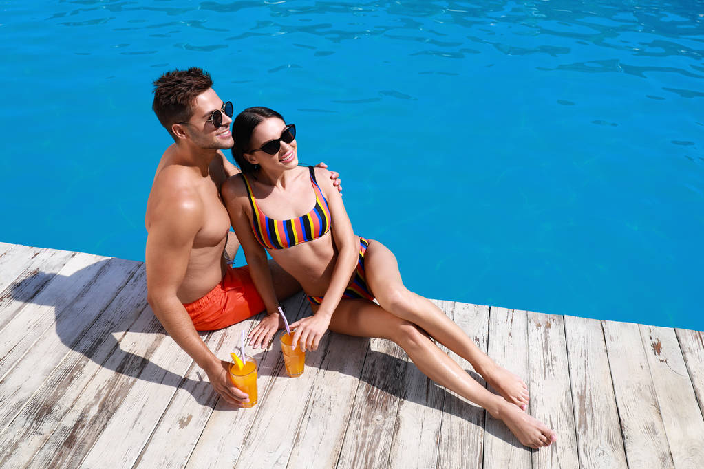 Mujer en bikini con novio cerca de piscina al aire libre. Feliz pareja joven
 - Foto, imagen