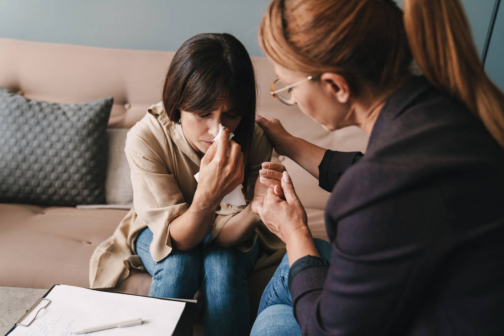 Photo of depressed caucasian woman crying and having conversation with psychologist in room - Photo, Image