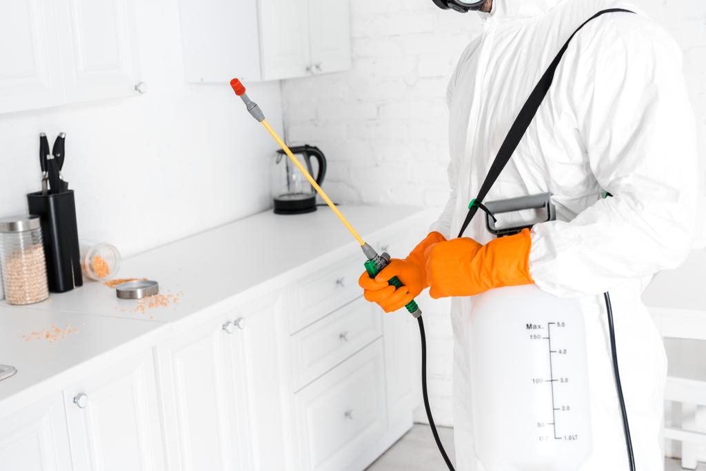 cropped view of exterminator holding toxic spray near kitchen cabinet  - Photo, Image