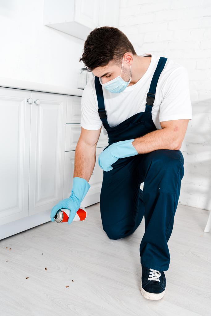 Exterminator skin in blauwe latex handschoenen houden spray kan in de buurt van insecten op de vloer - Foto, afbeelding