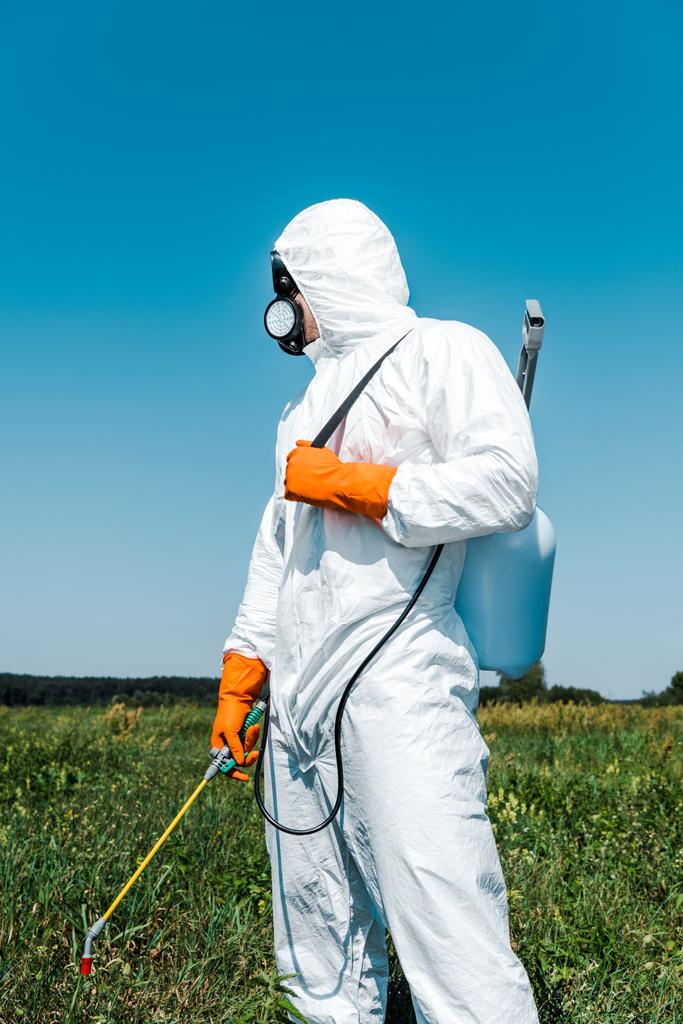 Exterminator skin in wit uniform en latex handschoenen houden spray  - Foto, afbeelding