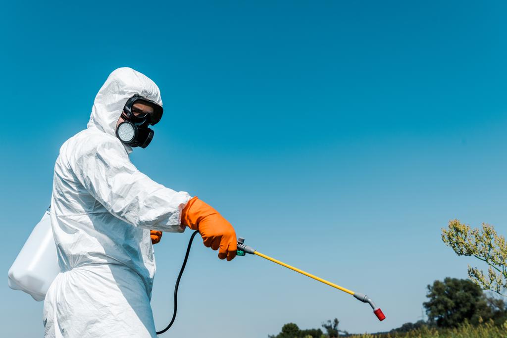 Exterminator skin in beschermende uniforme houder giftige spray buiten  - Foto, afbeelding