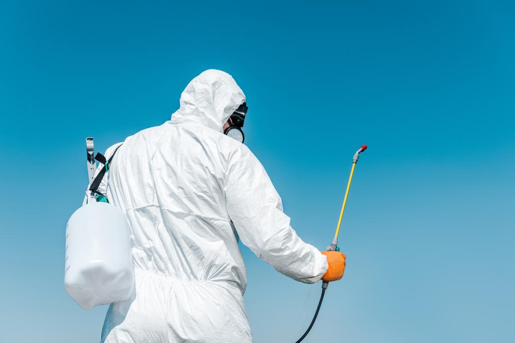 exterminator in white protective uniform holding toxic spray outside  - Photo, Image